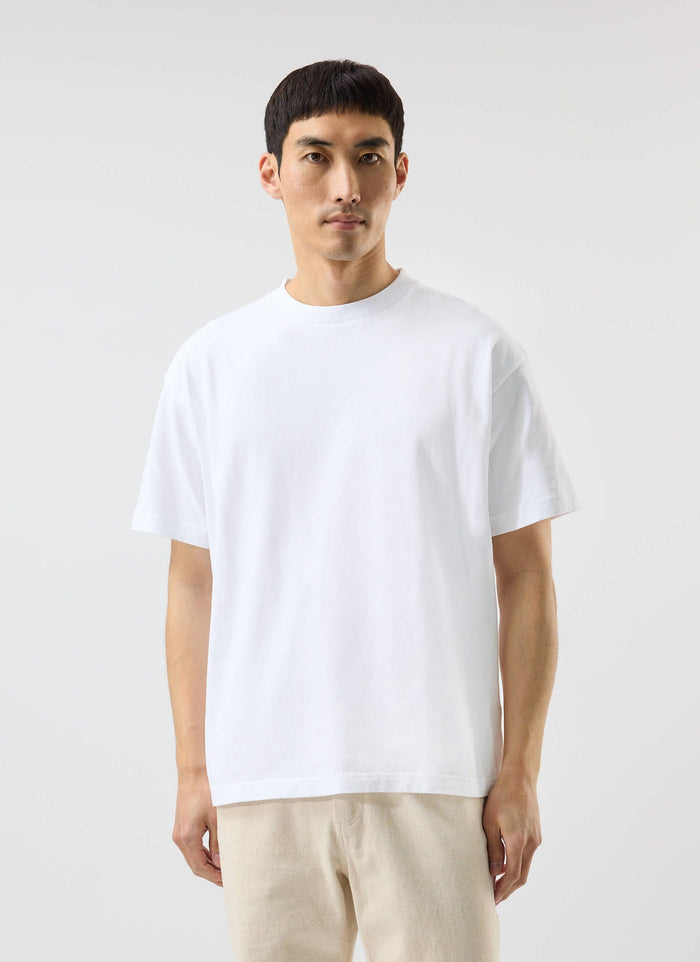 A model wears a white Percival oversized t-shirt, made from organic cotton, and light-coloured trousers.