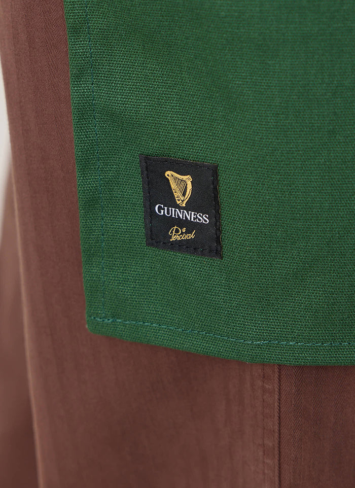 Close-up of the forest green Guinness x Percival apron, showing the woven brand label at the hem.
