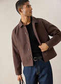 A model wears the espresso Percival Carter Cropped Jacket styled with a black t-shirt and blue jeans.