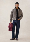 A model wears the Watcher Check Percival Carter Cropped Jacket with blue jeans and loafers in a studio shot.