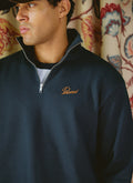 Close-up of a model wearing the navy Percival Conrad Funnel Neck 1/4 Zip Jumper in 100% cotton with an embroidered logo.