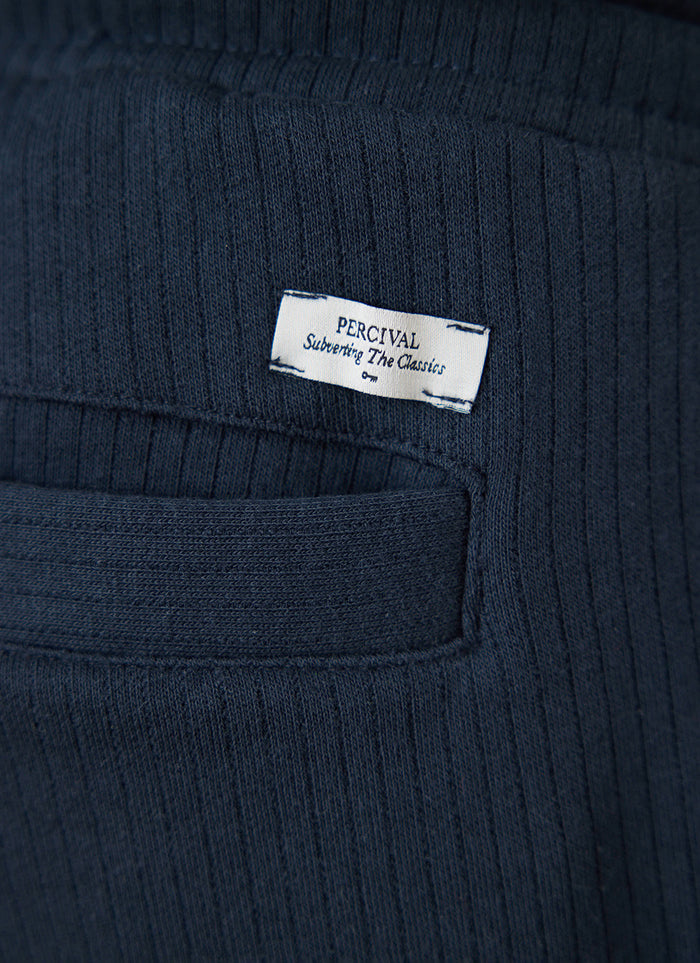 Close-up of the navy Percival Conrad trackpants showing the back pocket and branded label detail.