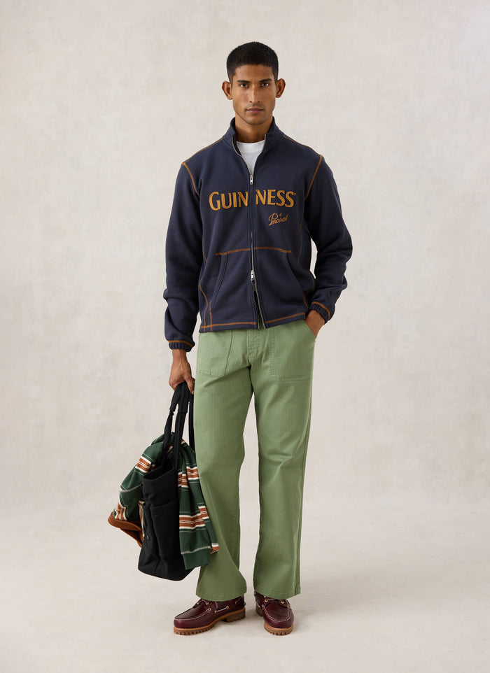Model wearing the navy Guinness x Percival funnel neck sweatshirt with contrast stitching and appliqué branding.