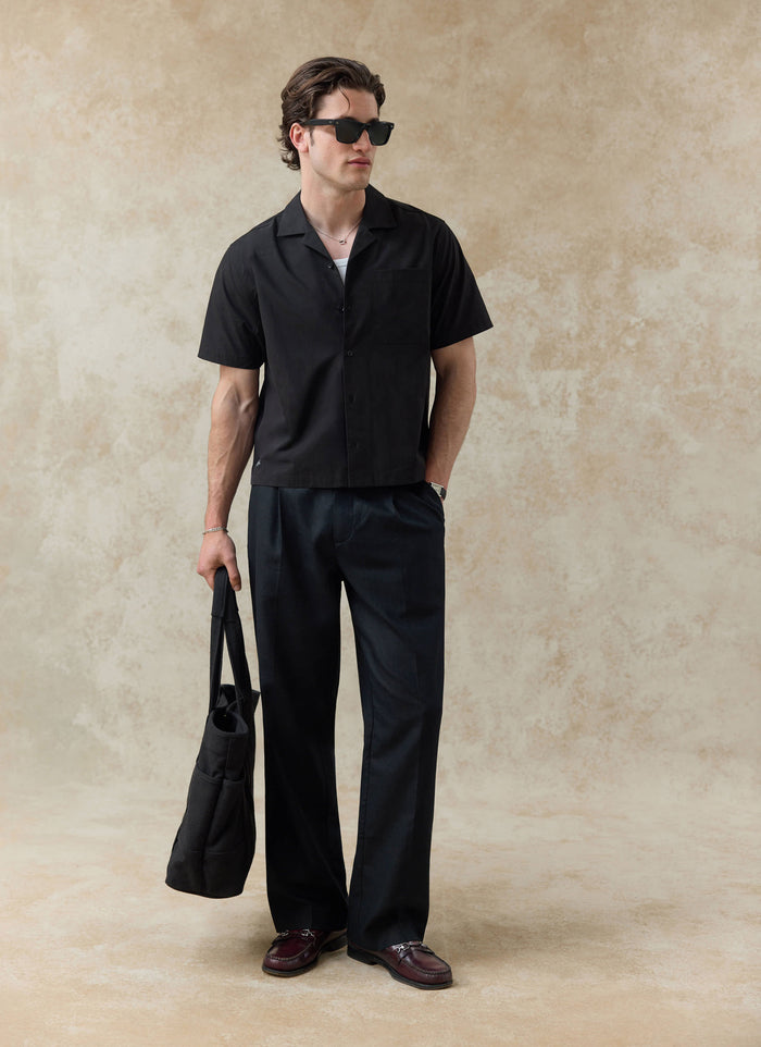 Black cotton Percival Daniel Boxy Cuban Shirt styled with matching trousers and a tote bag from the SS26 collection.