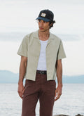 Percival Daniel boxy Cuban shirt in pistachio cotton, shown on a model by the coast as part of the SS26 collection.