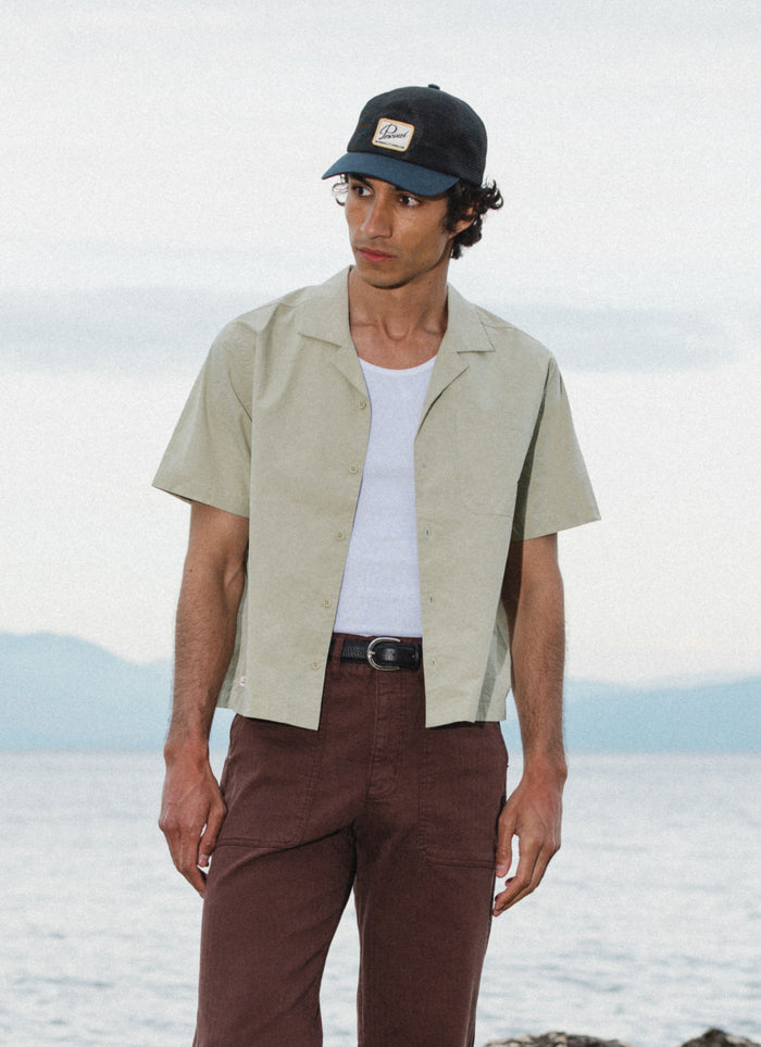 Percival Daniel boxy Cuban shirt in pistachio cotton, shown on a model by the coast as part of the SS26 collection.