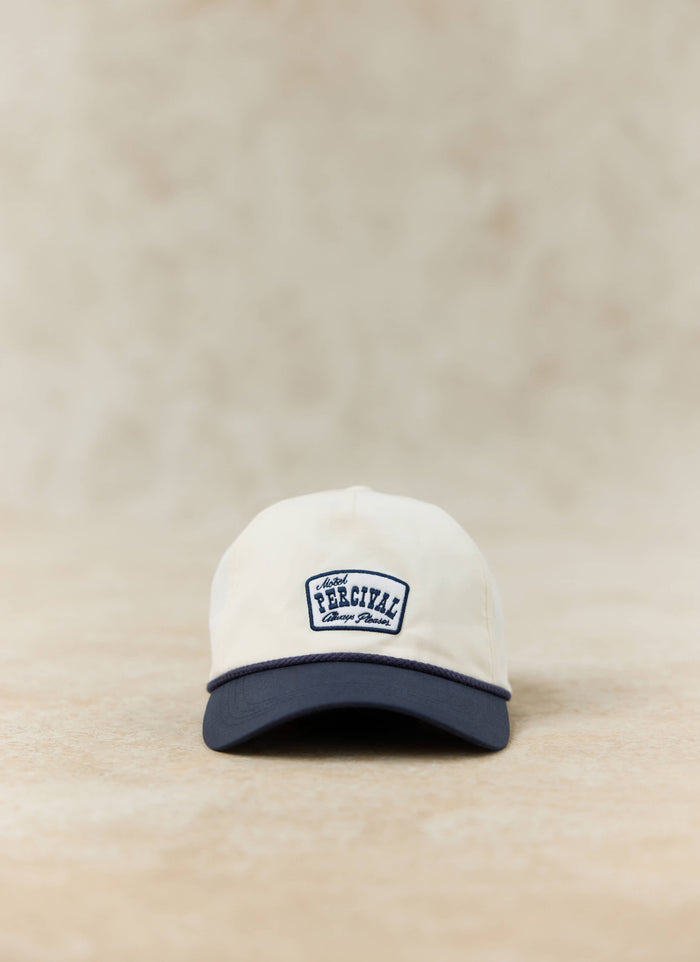 Percival Donovan soft trucker cap in cream with a contrast navy peak and motel-inspired embroidered patch.