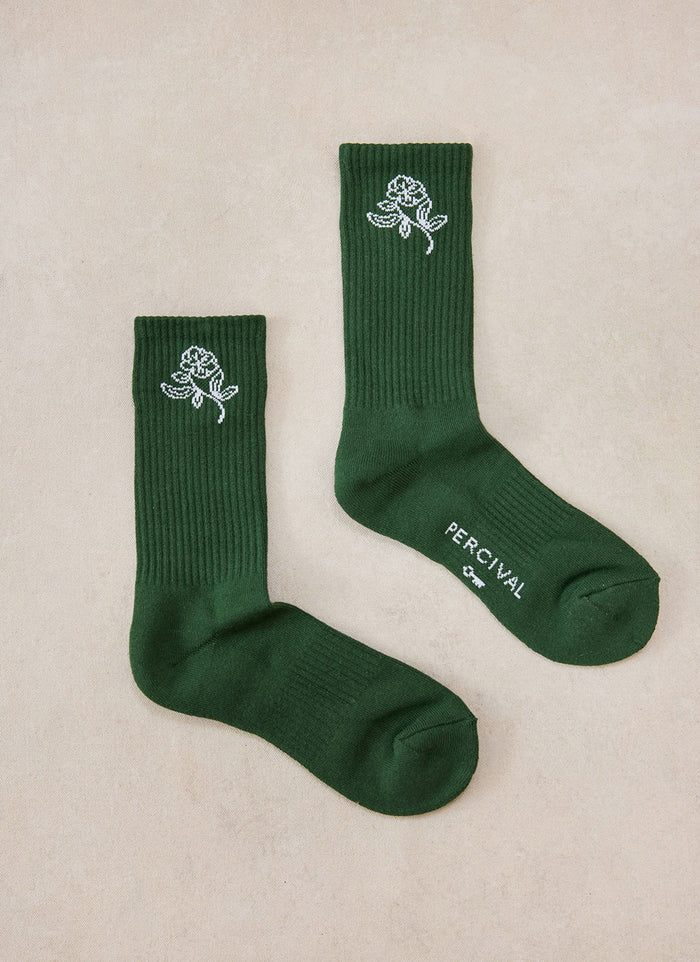 A flat lay of the forest green Earl Jacquard cotton socks featuring a white floral motif and Percival branding.