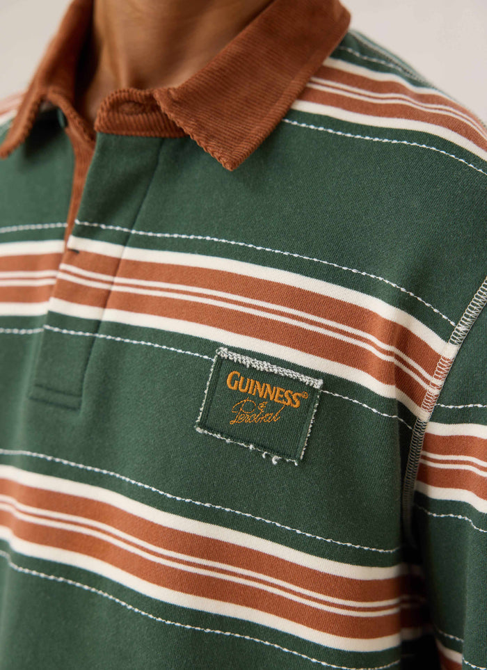 Close-up of the Guinness x Percival striped rugby shirt in green, showing the brown cord collar and chest patch.