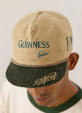 Close-up of the beige Guinness x Percival short peak cap featuring green corduroy brim and front embroidery.