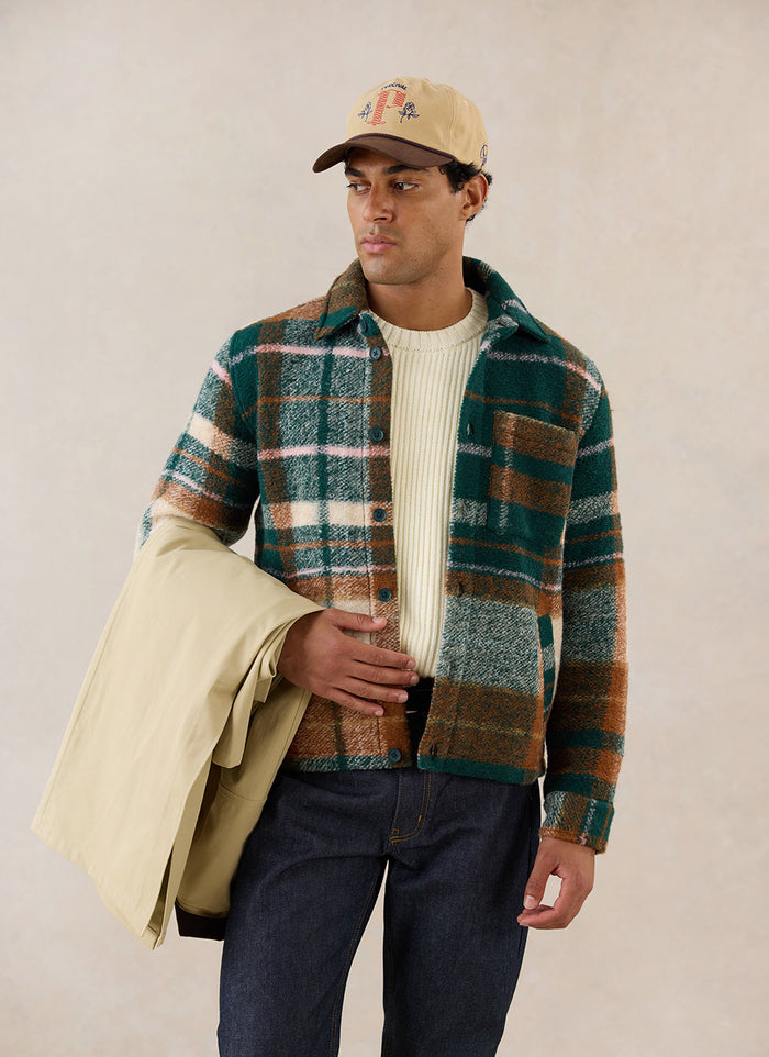 A model wears the Percival wool Knowles Overshirt, layered over a cream knit and holding a neutral outer layer.