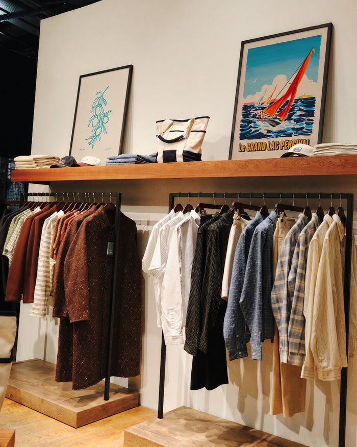 The Olive Branch and Le Grand Lac prints from Percival displayed on a store shelf above a rack of shirts.