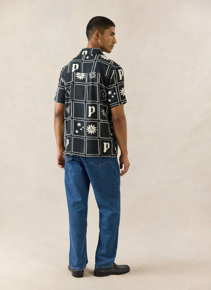 The Percival Lunar Panel Cuban Shirt in black viscose, featuring white celestial motifs, shown from behind on a model.