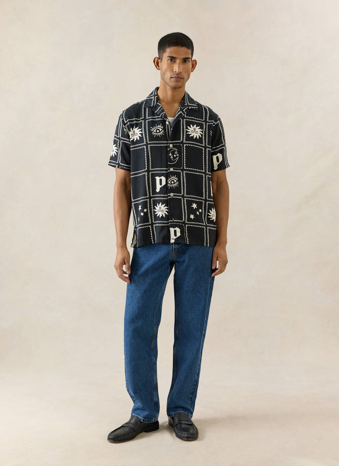 Black Percival Lunar Panel Cuban Shirt in viscose with a white celestial print, styled with blue jeans and black loafers.
