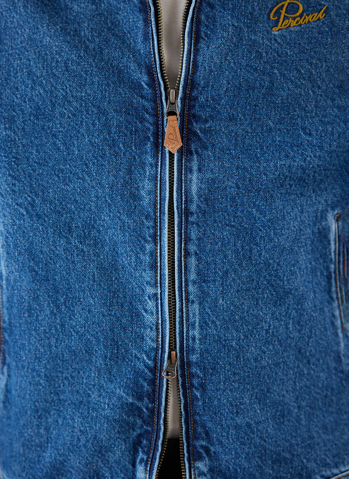 Close-up of the mid wash blue Percival Mackey Zip Jacket showing the zipper and chest embroidery detail.