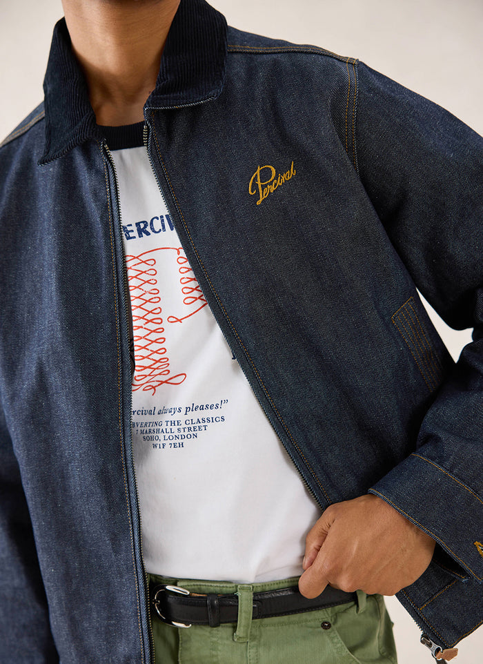 Close-up of the raw denim Percival Mackey Zip Jacket, showing the cord collar and embroidered chest detail.