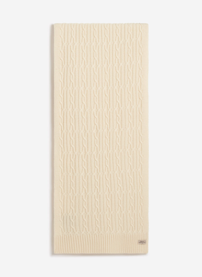 The Percival Melville Cable Knit Scarf in ecru wool, laid flat against a white background to show the intricate knit pattern.