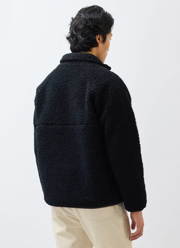 A model, seen from behind, wearing the black wool Quarter Zip Fleece Pullover from Percival.