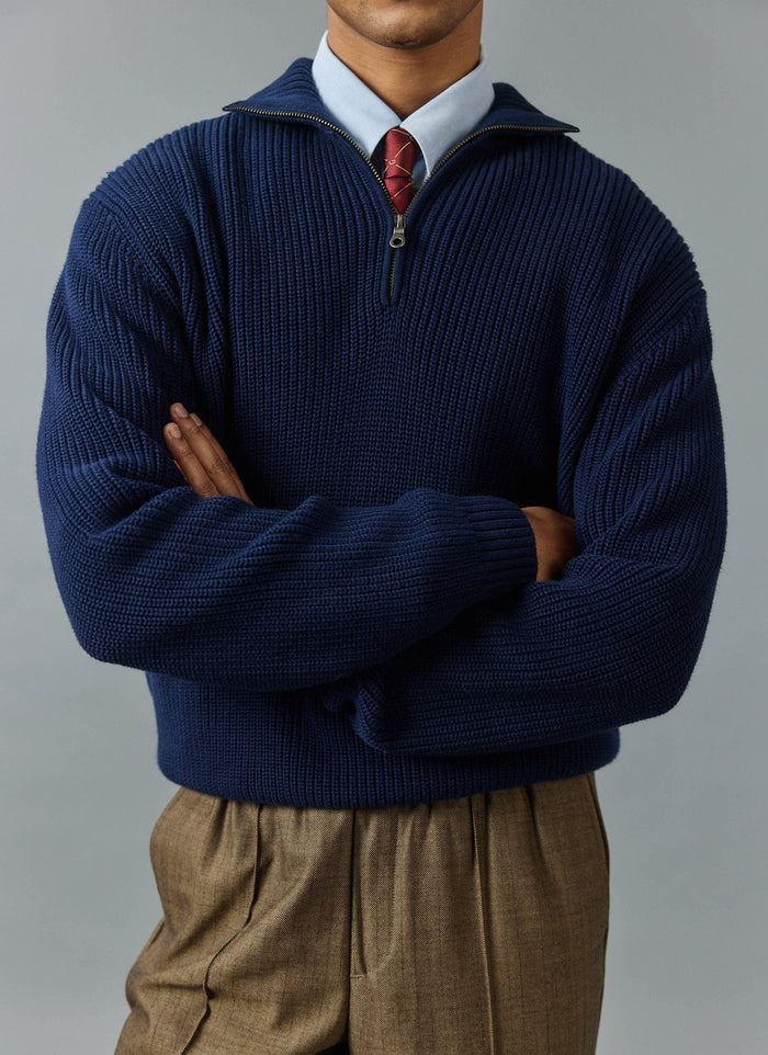A man models the navy Percival Meyer Boxy Quarter Zip jumper with arms crossed, layered over a blue shirt and patterned tie.