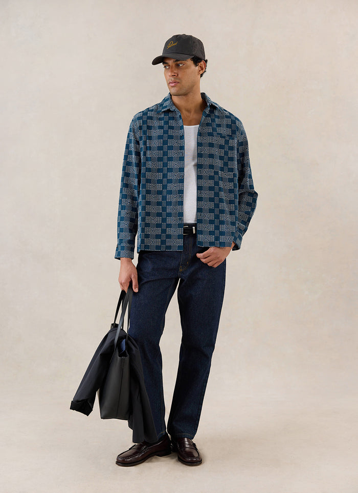 A model wears the navy Percival Nolan Jacquard Boxy Shirt with dark jeans, holding a black tote bag.
