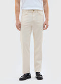 A model wears the Percival Rocco 5 Pocket Trousers in ecru, styled with a white vest and black loafers.
