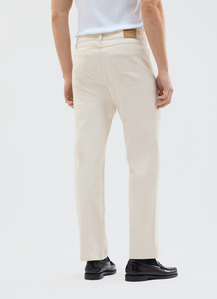 A model seen from behind wearing the Percival Rocco 5 Pocket Trousers in ecru herringbone cotton with black loafers.
