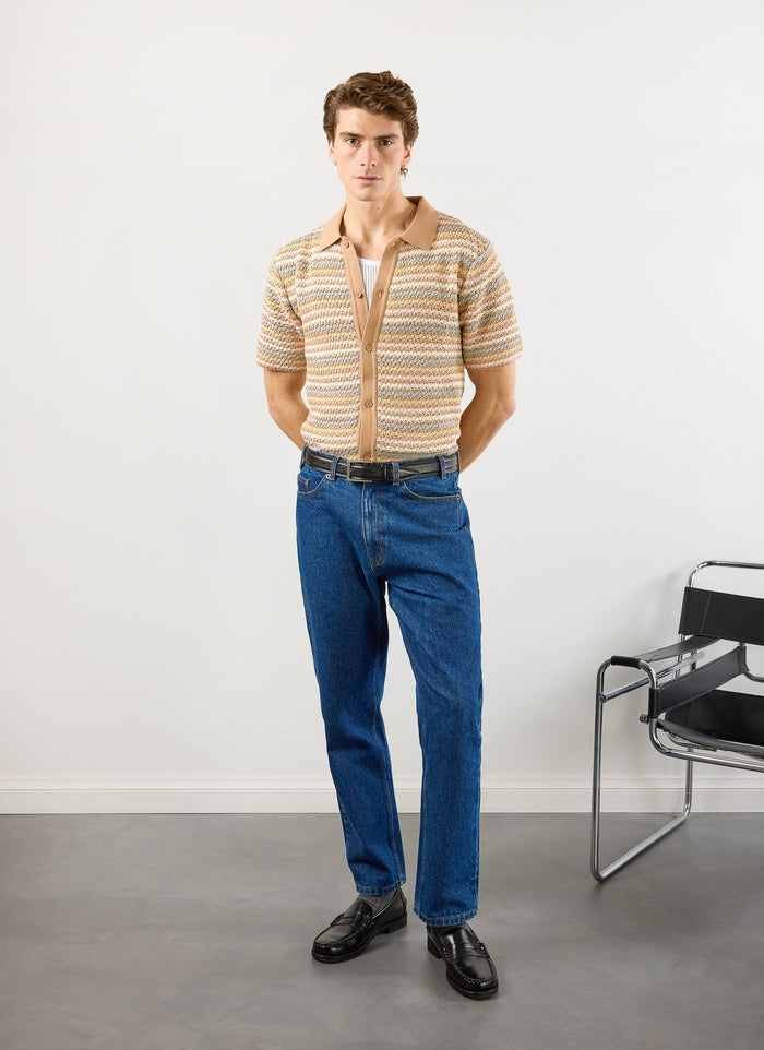 full length shot of a model wearing the percival sari stripe knitted shirt in ecru with blue jeans and black loafers