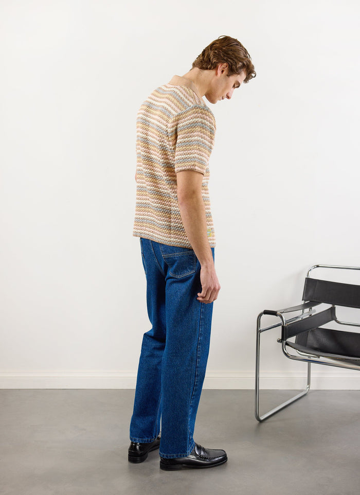 Side view of a model in the Percival Sari Stripe Knitted Shirt in ecru, styled with blue jeans and black loafers.