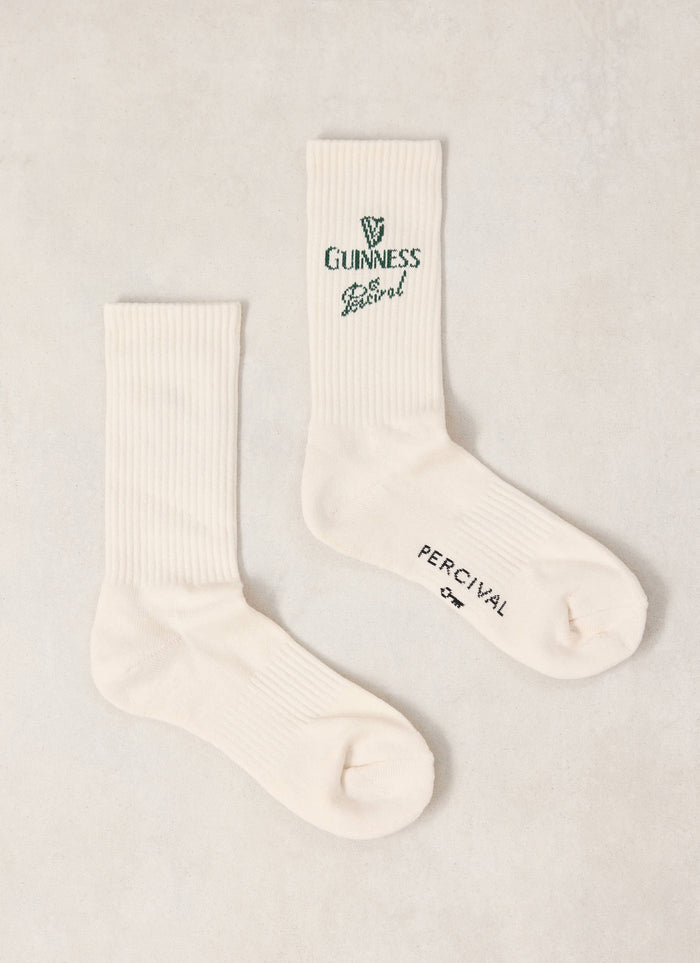 Pair of Guinness x Percival cream ribbed crew socks featuring green branding and text details.