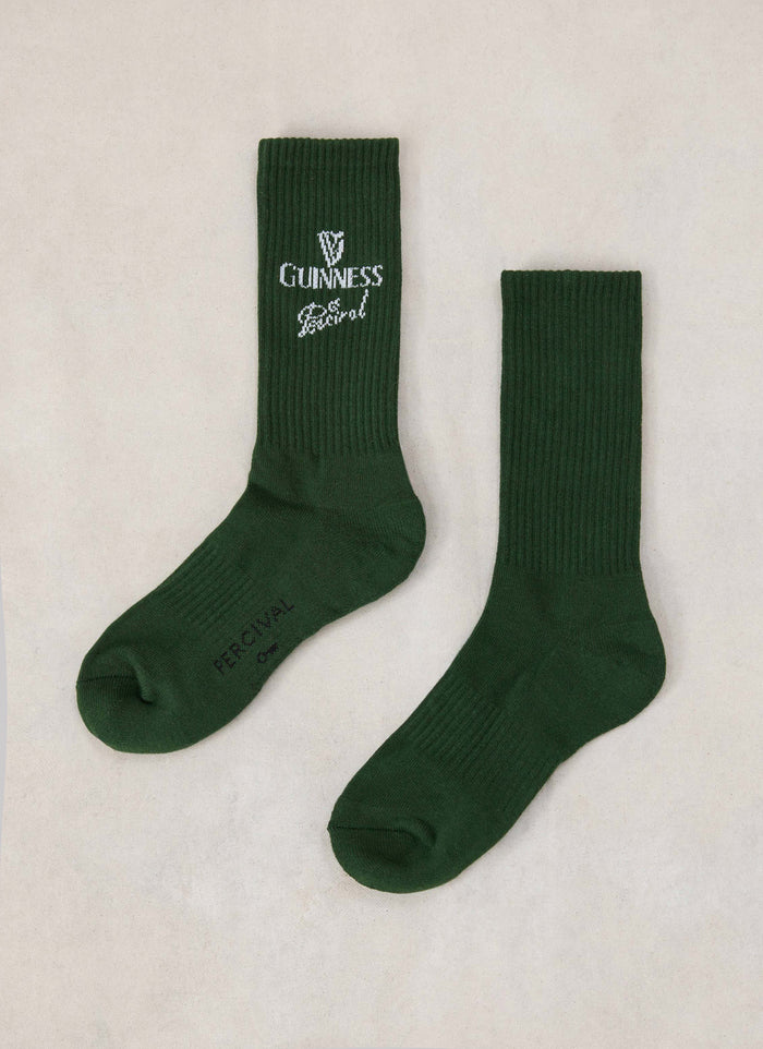 A pair of Guinness x Percival crew socks in forest green cotton blend with ribbed texture and knitted branding.