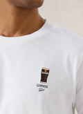 A close-up of the white Guinness x Percival stout embroidered T-shirt showing the chest graphic detail.