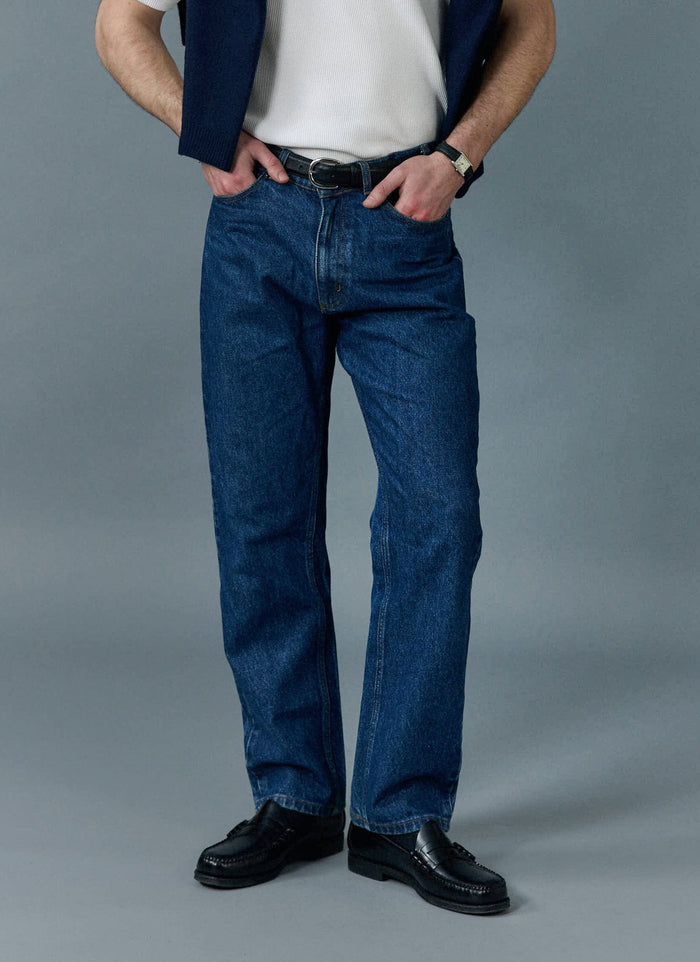 A model wears the Percival Straight Leg Denim Jeans in Mid Wash Blue, styled with black loafers and a white t-shirt.