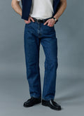 A model wears the Percival Straight Leg Denim Jeans in Mid Wash Blue, styled with black loafers and a white t-shirt.