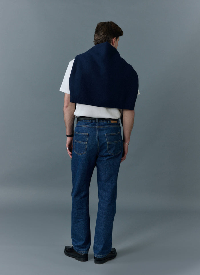 Man from behind wearing Percival's mid wash blue straight leg jeans with a white t-shirt and navy knit over his shoulders.