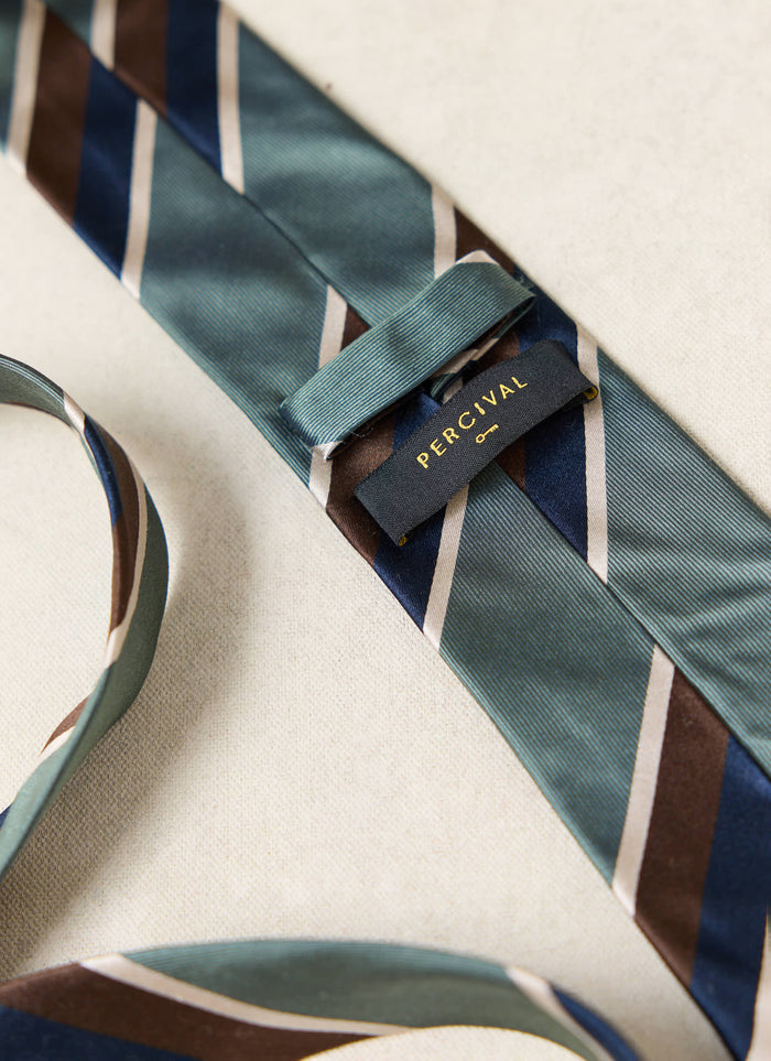 Percival Stripe Tie | Silk | Multi, a close-up showing the forest green, navy and brown stripes and woven label.