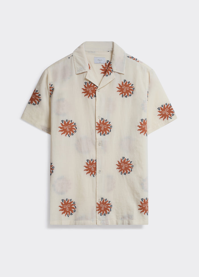 The Percival Sun Shirt in ecru, a lightweight camp collar shirt with an orange sun print, shown against a grey backdrop.
