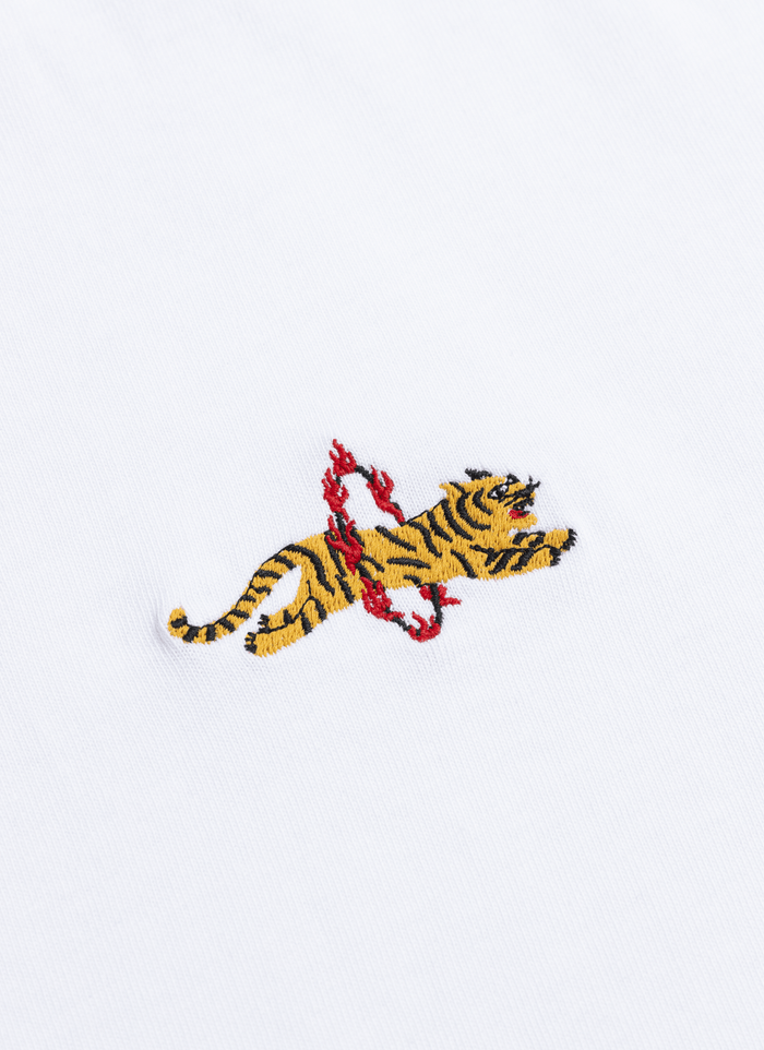 Close-up of the embroidered flaming tiger detail on the white organic cotton Tiger T-shirt by Percival.