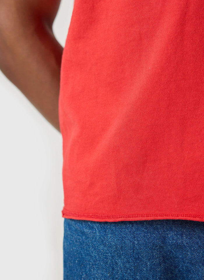 Close-up shot of the raw hem detail on the red Track and Field t-shirt from the Champion x Percival collection.