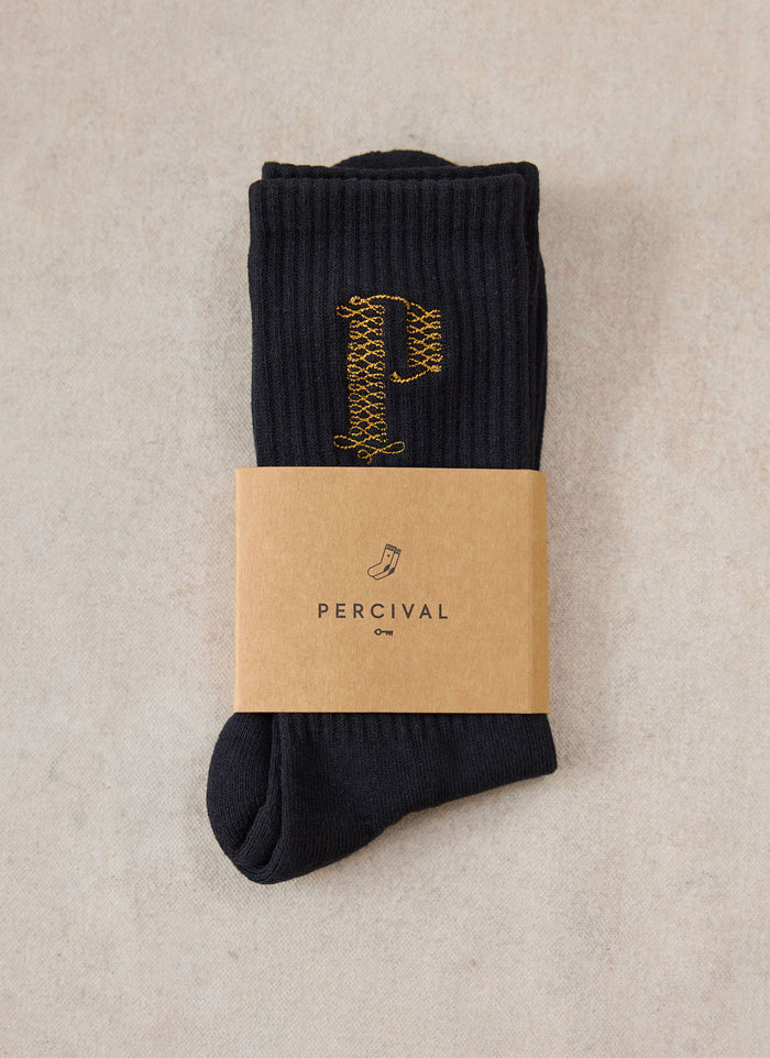 A pair of black Percival Tucker embroidered socks wrapped with a branded paper band.